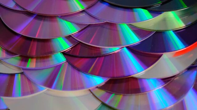 Reflection of the surface of a DVD discs, multiple optical discs stacked on top of each other like fish scales, colorful lines on the surface are caused by thin-film interference and diffraction