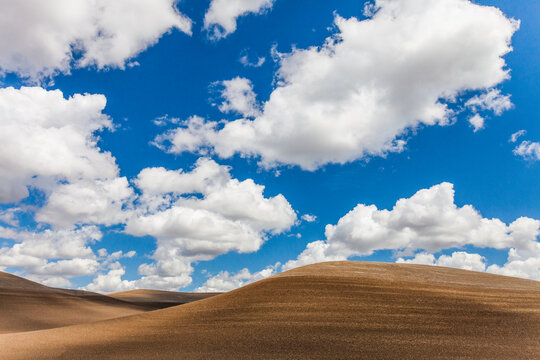 Blue sky and clouds over brown rolling hills