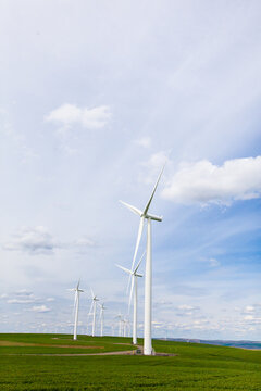 Wind turbines in a row on green rolling hills