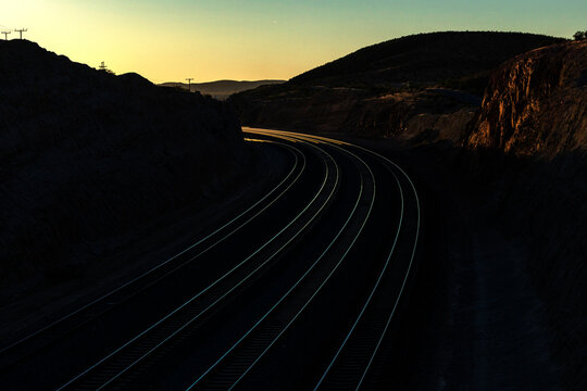 Curving railroad tracks through a canyon at sunset