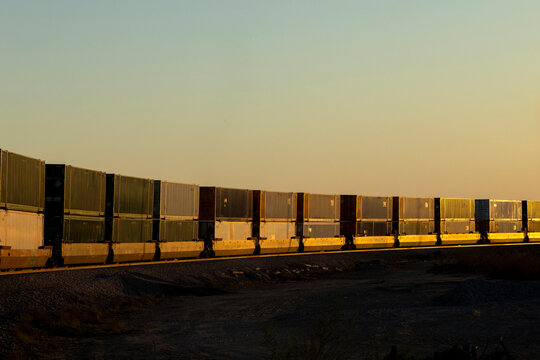 A long freight train with containers at sunset