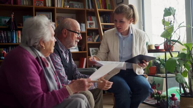 Financial advisor helping senior couple with savings, showing them savings calculator in laptop.