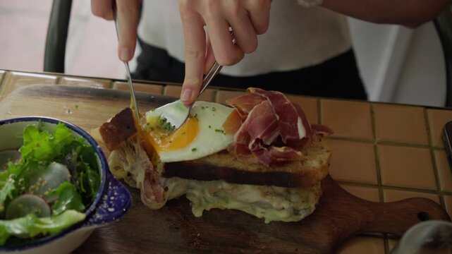 Person cutting a croque madame sandwich for breakfast