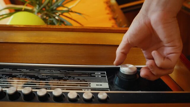 Person's hand tuning old soviet radio receiver