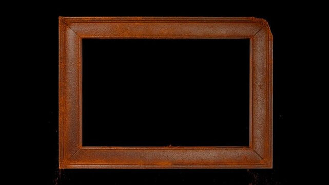 Static shot of rectangular picture border with rust colored powder falling and settling on black background in studio