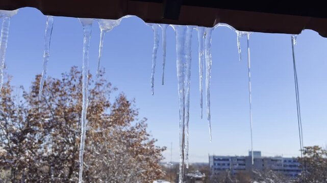 Close-Up Icicles Above Window With Winter Sky and City Background