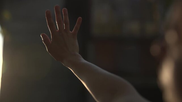 Backlit hand raised in a dark indoor scene