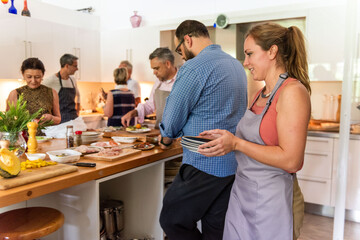 Obraz premium Group of people cooking together in a bright kitchen setting.