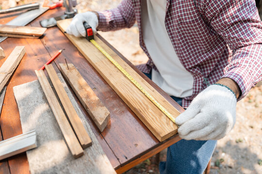 Portrait carpenter man working on DIY woodworking project at home workshop. Skilled craftsman using tools for handmade furniture, home improvement and sustainable lifestyle concept.