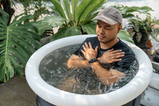 Man practices cold therapy and ice bathing in inflatable tub, using Wim Hof Method for wellness, meditation, fitness recovery, sports therapy. Wellness and healthy lifestyle.