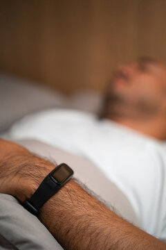 Use a smartwatch to track sleep and check for quality sleep. Young man lying in the bed at night. Man sleeping well in comfortable cozy fresh bed on soft pillow linen. Health and rest concept.