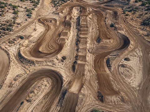 Aerial drone view over dusty off road motocross track with jumps and sharp racing berms