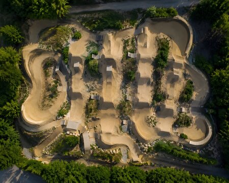 Sky view urban dirt jump park ramps berms patterned tracks extreme cycling facility composition scene