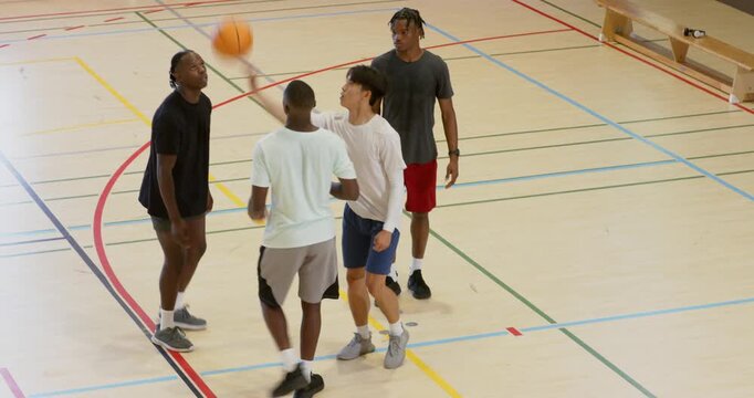 Passing ball, diverse male athletes dribbling, tipping rebound and sprinting in gym to secure ball