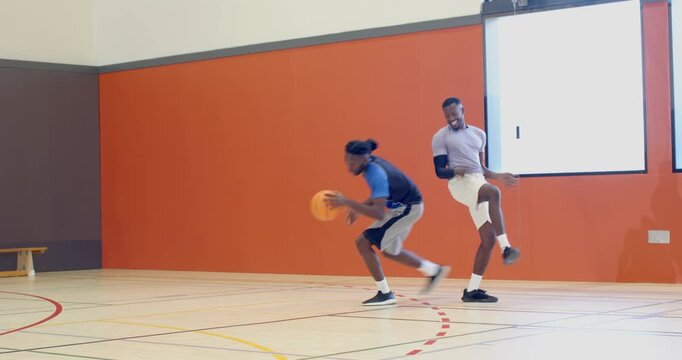 African american players dribbling ball gauging defender making spin shot scoring on gym