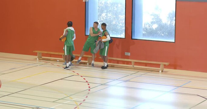 Diverse male basketball teammates huddling, walking from bench after timeout, ball, copy space