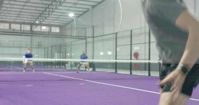 Opponent driving triggers male player, volleying ball on paddle court regaining control, copy space