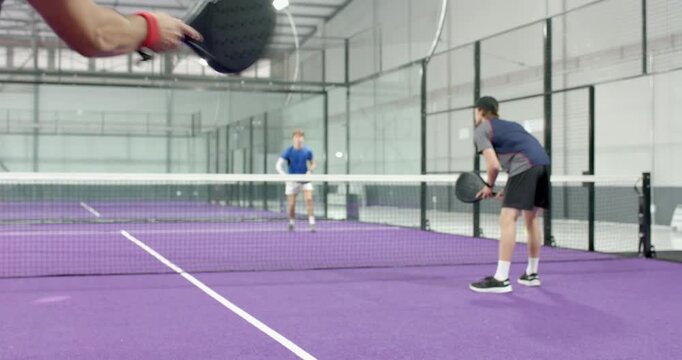 Diverse male players tossing ball, serving underhand indoors, starting back-and-forth volley