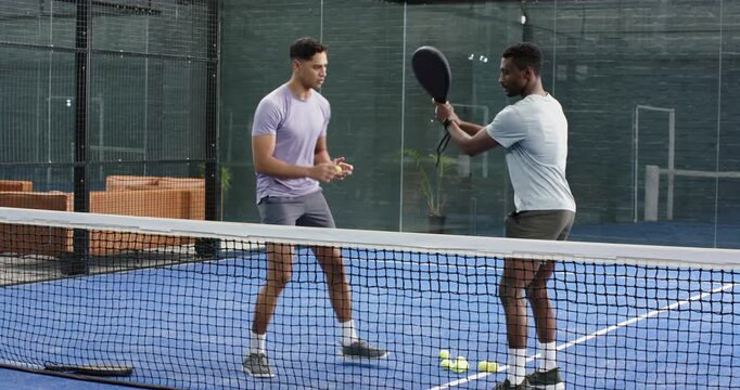 Male coach with student practicing swings after positioning racket, sharing handshake on court