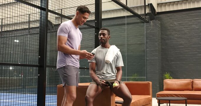 male coach and athlete taking smartphone observing drills onscreen, fistbumping on couch