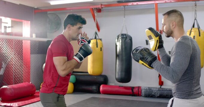 Indian male trainee boxer following coach moving focus mitts throwing jab cross combos
