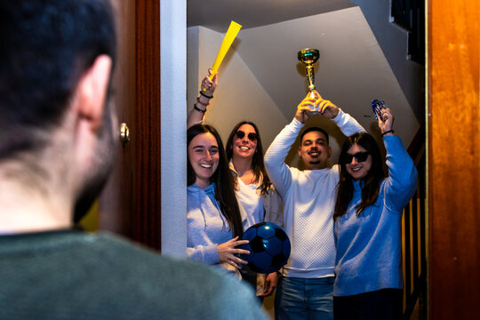 Group of excited friends arriving at a doorway, celebrating a sports win