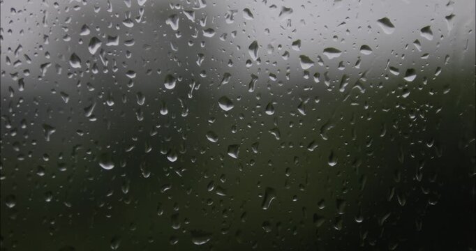 Raindrops are running down the window glass. Bad weather outside. Rain storm and thunderstorm outside the window.