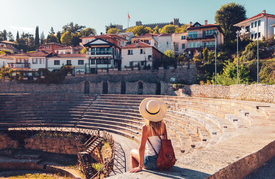 Young female tourist admiring the ancient Roman theater in Ohrid, authentic travel, exploration and historical heritage concept in North Macedonia