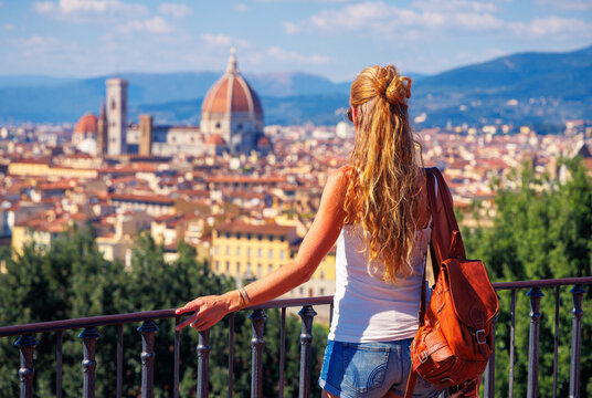 Young female traveler with leather backpack looking at Florence cathedral skyline, authentic lifestyle photography and summer vacation concept in Italy