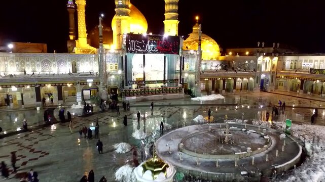 Magnificent low angle shot from the main courtyard showing the glowing entry gates and beautiful central architecture of the holy shrine of Lady Masoumeh in Qom city at night scenery.
