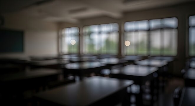 Abstract blurred background of an empty dark classroom with rows of desks.