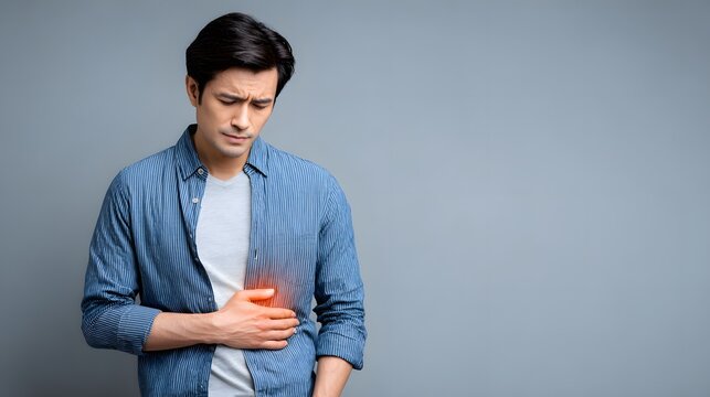 Asian man holding liver area with painful expression, glowing red liver graphic, healthcare photography