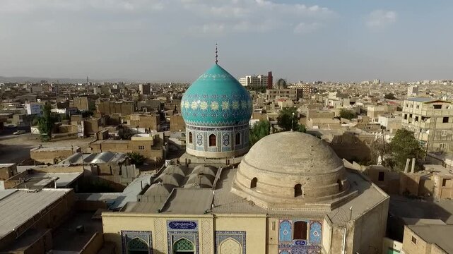 Professional aerial shot highlights intricate tile work on blue mosque dome with surrounding traditional rooftops and city layout.