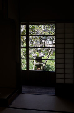 Traditional Japanese stone lantern in zen garden viewed through house window
