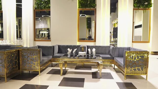 Stylish luxury wedding reception lounge featuring elegant gold furniture, velvet sofas, decorative tables, modern lighting, mirrors, and sophisticated interior design. Ideal for wedding events, 