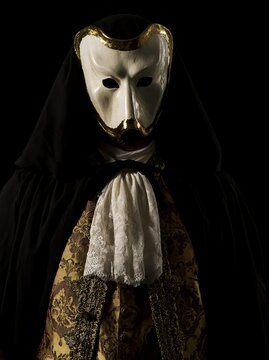 A nobleman wearing a Venetian Bauta white lacquered carnival mask with gilded edges