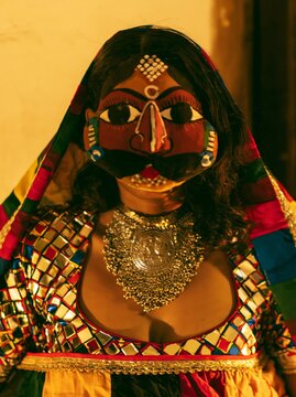 A woman wearing a Rajasthani Kathputli puppet-style painted mask