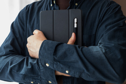 Man clutching a tablet with stylus attached in folio case for product mockup banner and website hero background