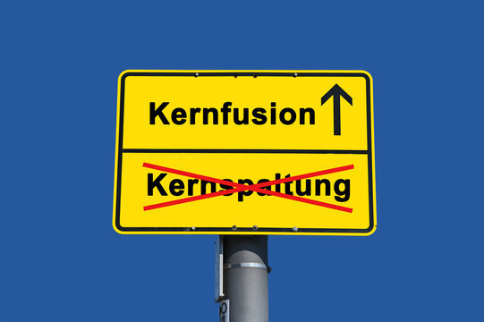 Sign Indicating Shift From Nuclear Fission (German: Kernspaltung) to Nuclear Fusion (German: Kernfusion) Concept Against Blue Sky