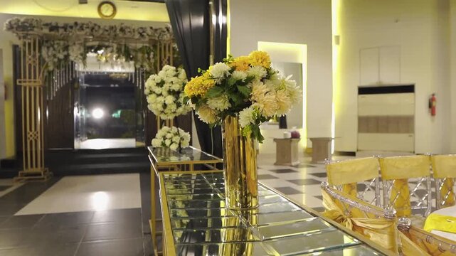 Beautiful wedding banquet hall interior featuring elegant blush rose flower centerpiece decoration on a reception table. Luxury floral arrangement in a stylish event venue with soft lighting,