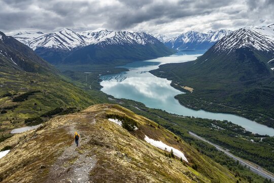 Climbers on a hiking trail on Slaughter Ridge, views of snowy mountains in spring and turquoise Lake Kenai Lake, Cooper Landing, Kenai Peninsula, Alaska, USA