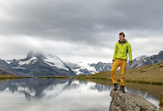Hiker stands on rock, Lake Stellisee, behind Matterhorn, cloudy, Wallis, Switzerland