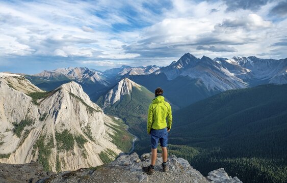 Hiker looking into the distance, mountain landscape with river valley and peaks, peaks with orange sulphur deposits, Overturn Mountain, panoramic view, Nikassin Range, Sulphur Skyline, near Miette Hotsprings, Jasper National Park, Alberta, Canada