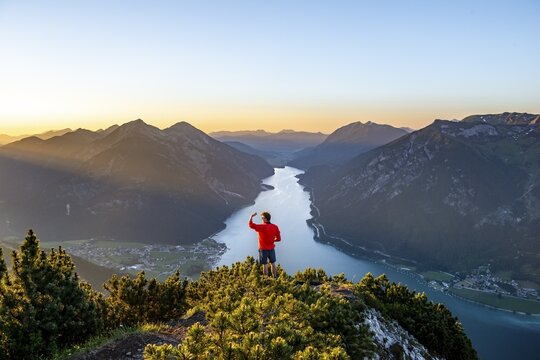 Sunset, young man looking over mountain landscape, view from the top of the B&auml;renkopf to the Achensee, left Seebergspitze and Seekarspitze, right Rofangebirge, Tyrol, Austria