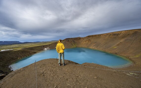 Tourist at volcanic crater with blue lake, volcanic lake, crater lake Viti at central volcano Krafla, Myvatn, North Iceland, Iceland