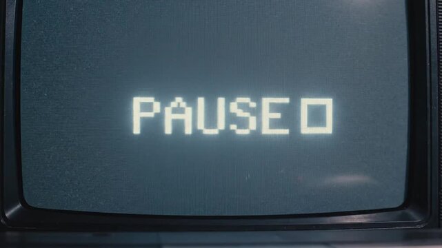 A vintage television screen displays the word paused with static noise