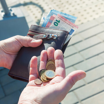 Leather purse, euro banknotes and coins in female hands, selective focus.