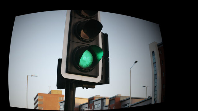 Green traffic light close up, go signal on city street semaphore with urban buildings background, transportation and safety concept