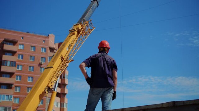 Construction worker standing near crane at building site