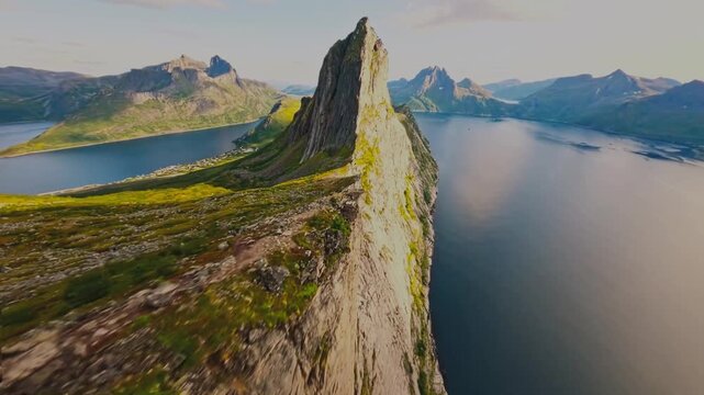 A breathtaking cinematic drone shot of Norway's rugged coastline, with the deep blue sea stretching endlessly on one side and dramatic landforms on the other. The aerial perspective follows the shorel